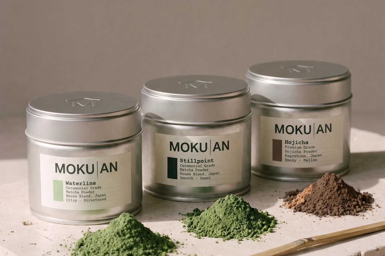 Die drei Dosen Waterline, Stillpoint und Hojicha von MOKU-AN, vor jeder ein kleines Häufchen Pulver